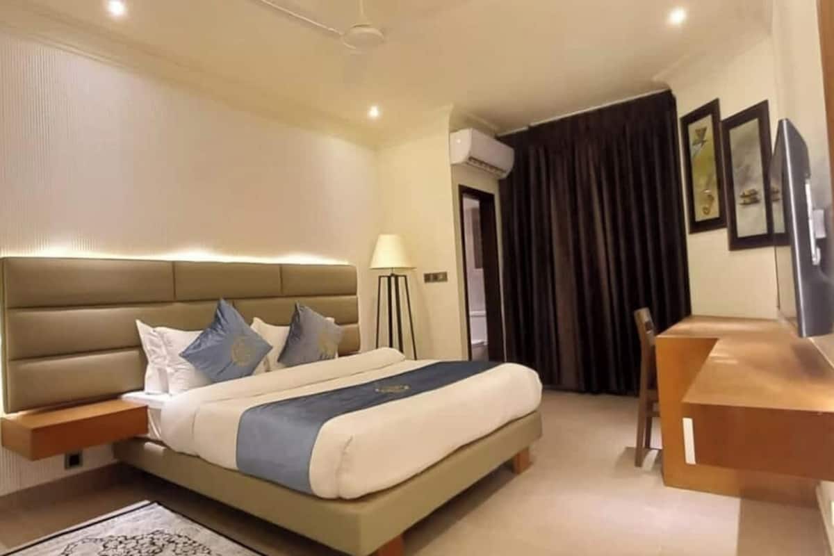 A modern hotel room with a large bed, bedside tables, a desk, and a chair.
