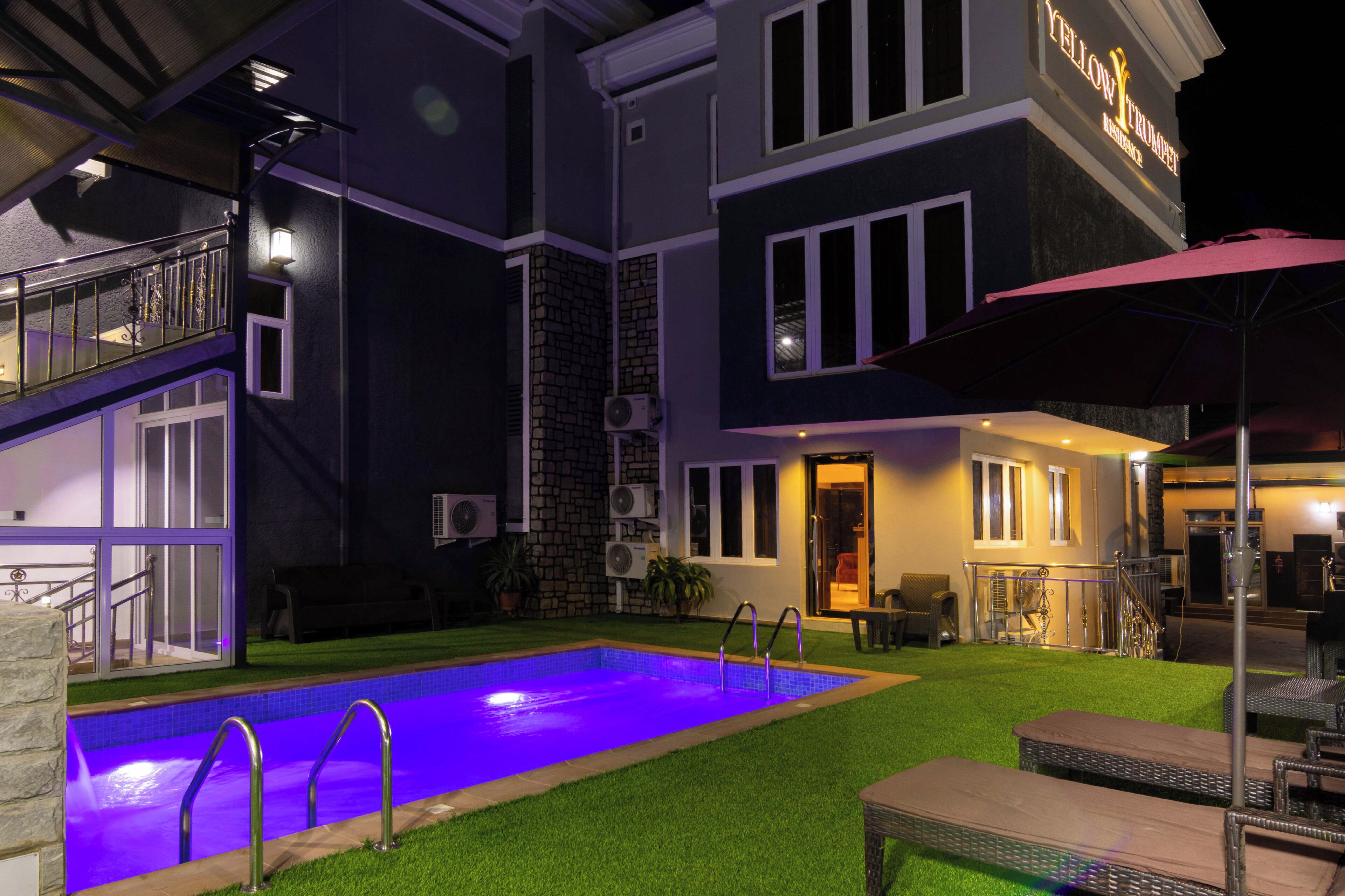 A two-story building with a swimming pool, outdoor seating, and a staircase leading to the upper level.