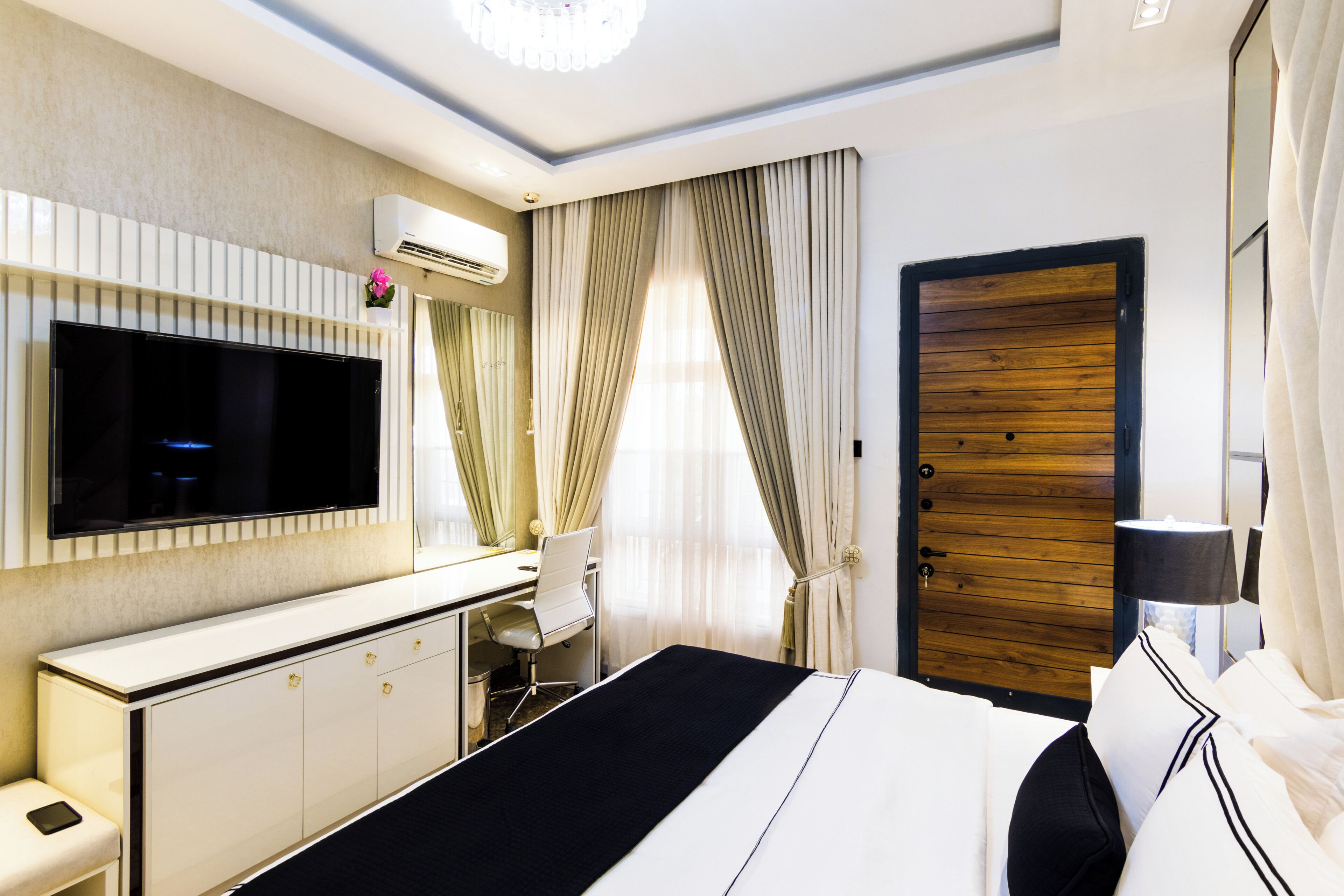 Une chambre d’hôtel comprenant un lit, un bureau, une chaise, une télévision et une armoire.