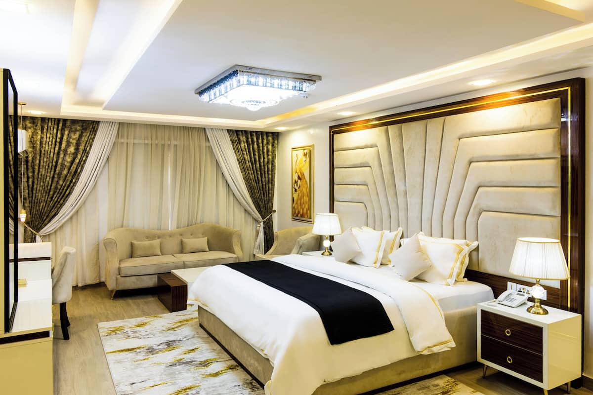 Une chambre d’hôtel moderne avec un grand lit, un canapé, une table de chevet et un lustre.
