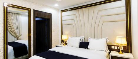 A hotel room with a large bed, two bedside tables with lamps, a mirror, and a door.