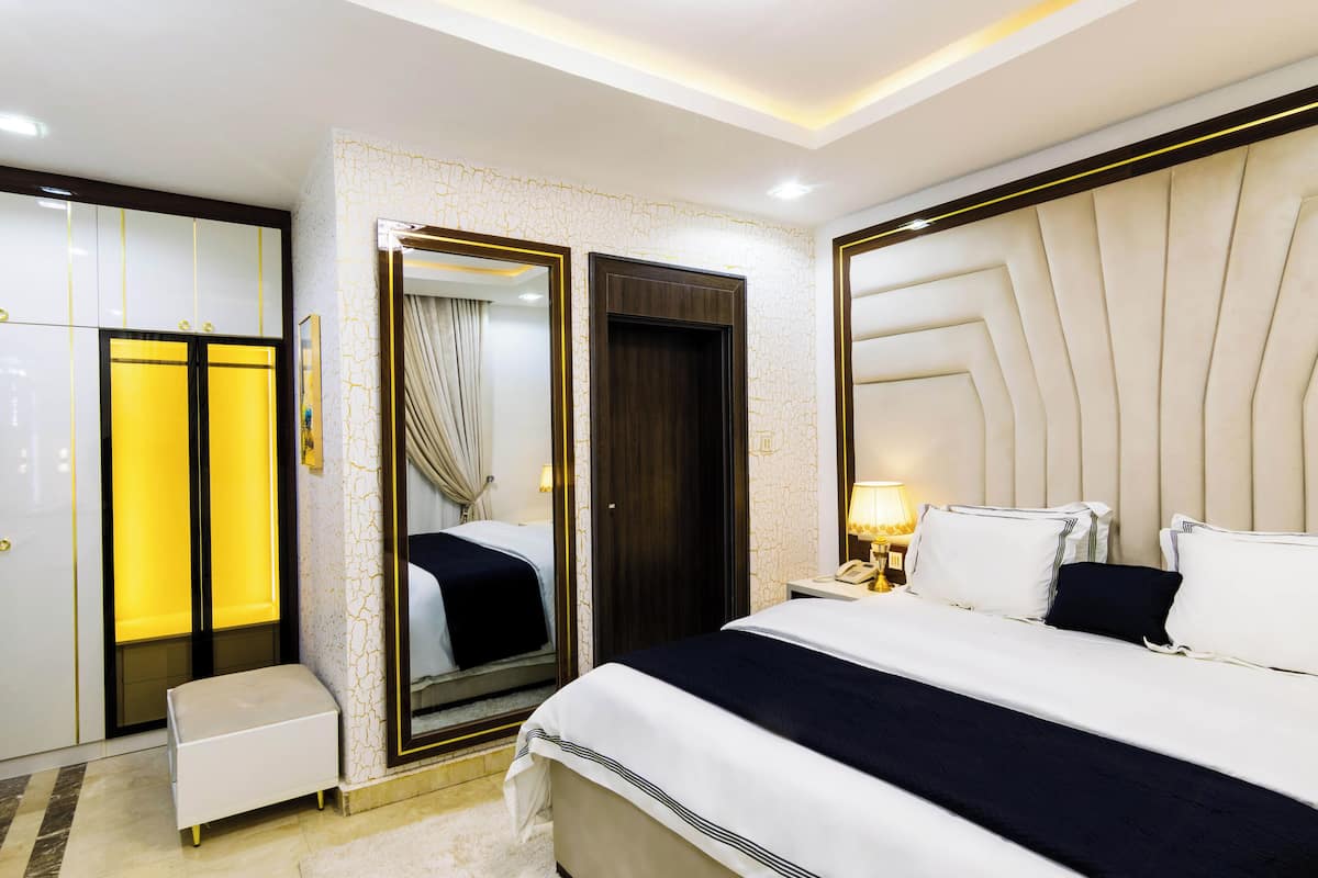 Une chambre d’hôtel moderne avec un grand lit, une armoire et un miroir.