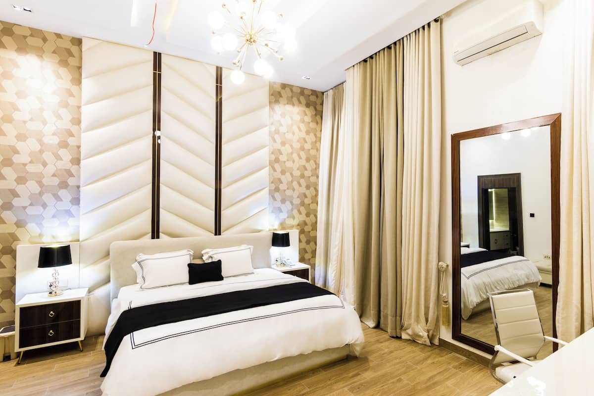 Une chambre d’hôtel moderne avec un grand lit, deux tables de chevet, un miroir et une vue sur la salle de bain.