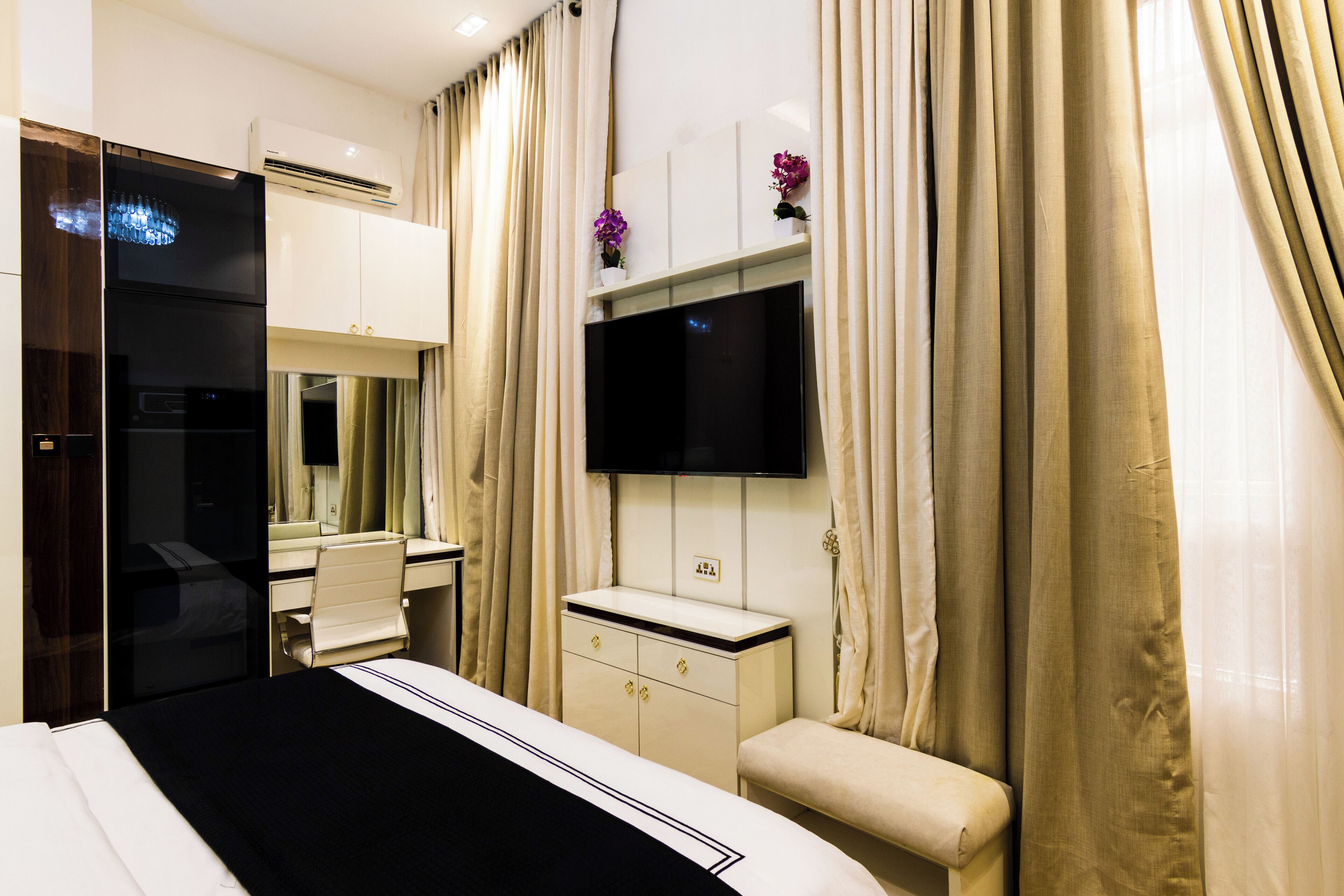 A hotel room with a bed, a desk, a TV, and a wardrobe.