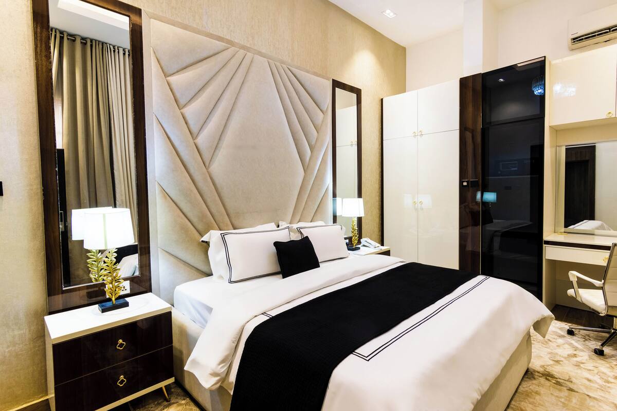 Une chambre d’hôtel avec un grand lit, un bureau avec une chaise, un miroir et une armoire.