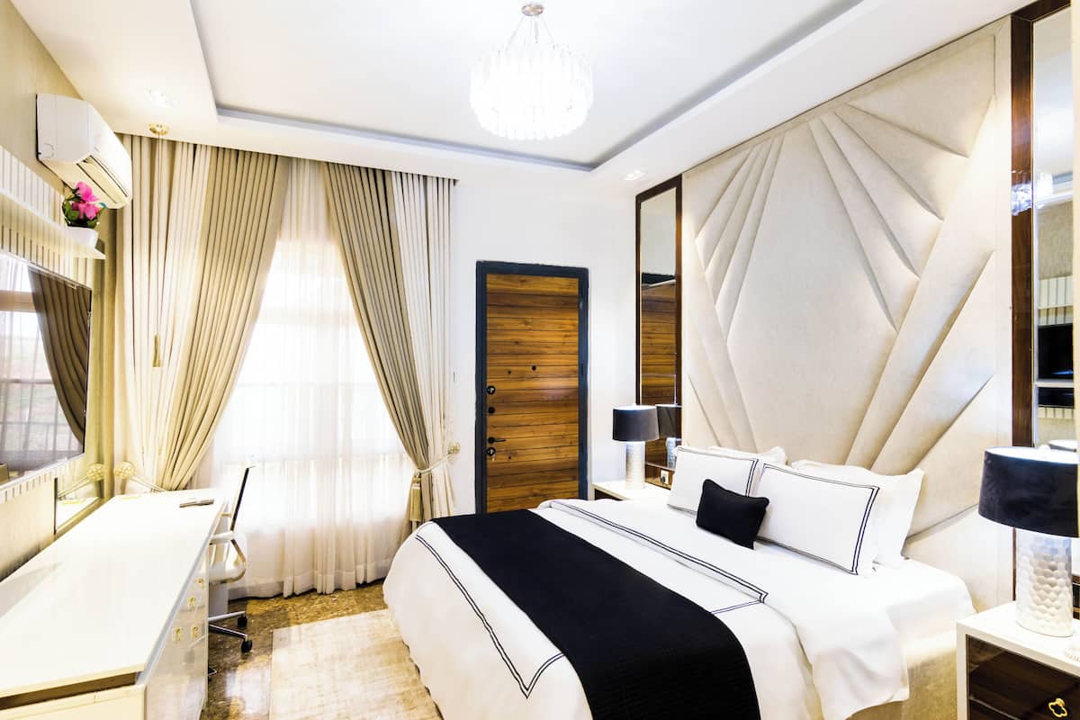 Une chambre d’hôtel avec un lit, un bureau, une chaise et un grand miroir.