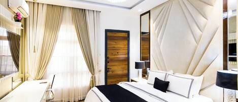 Une chambre d’hôtel avec un lit, un bureau, une chaise et un grand miroir.
