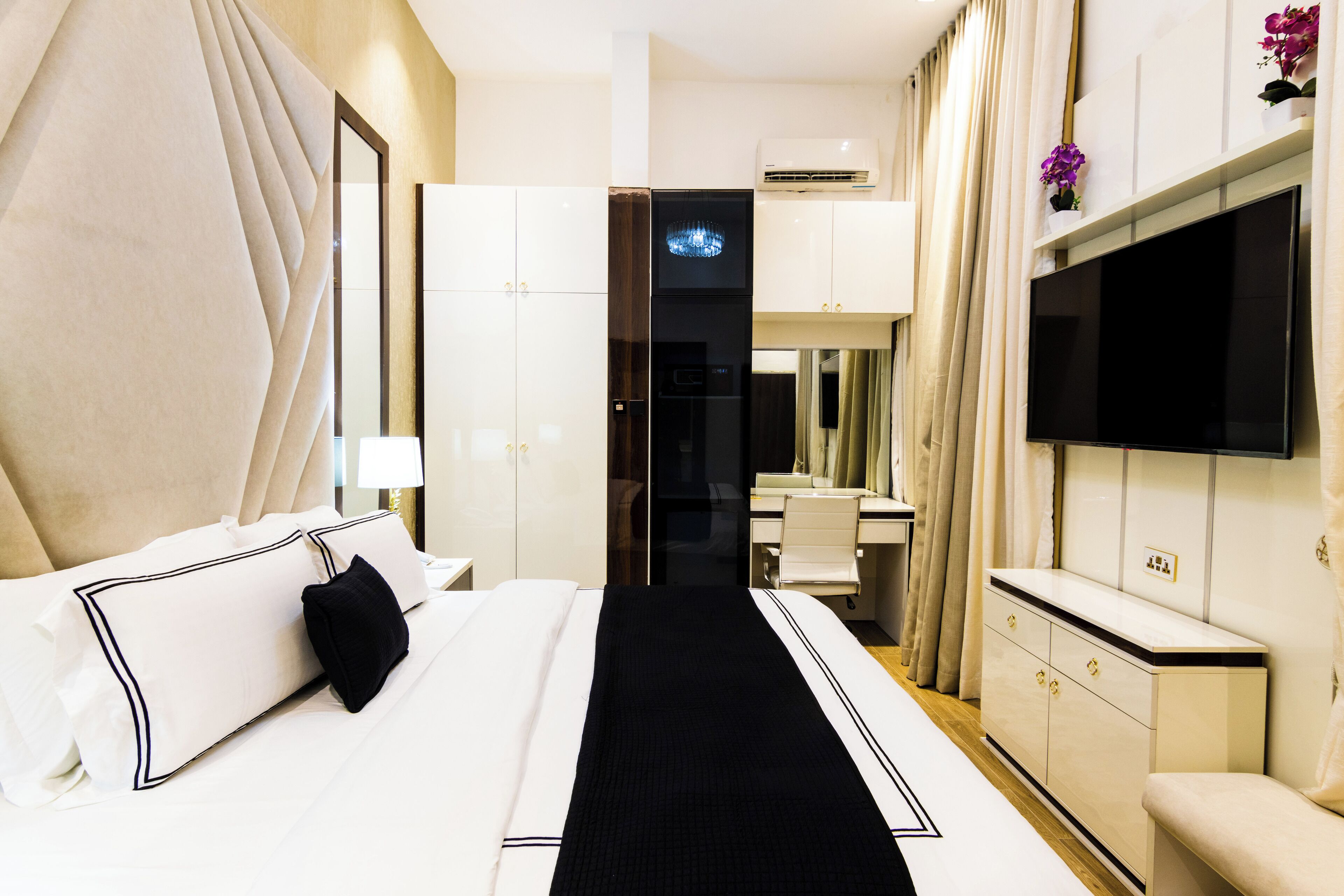 A hotel room with a bed, a desk, a TV, and a wardrobe.
