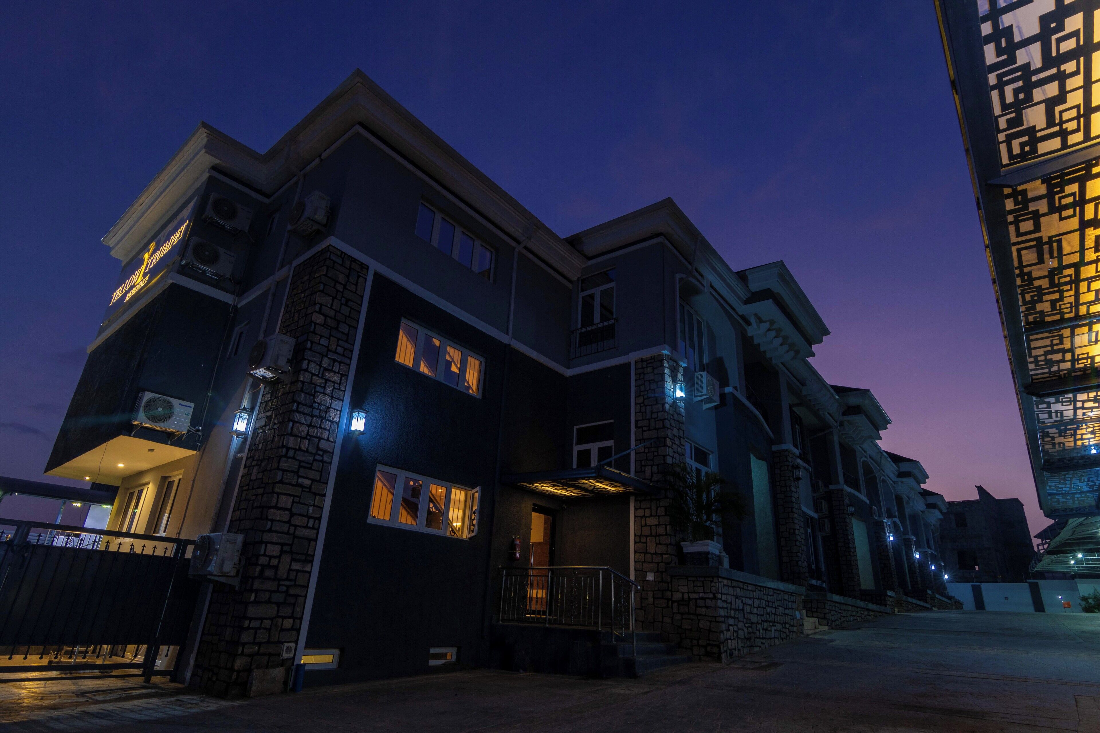A multi-story building with a dark facade, multiple windows, and a gated entrance.