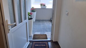 A hotel entrance with a welcome mat, a glass door, and potted plants outside. - Apartment Belisima Delux (Rab)
