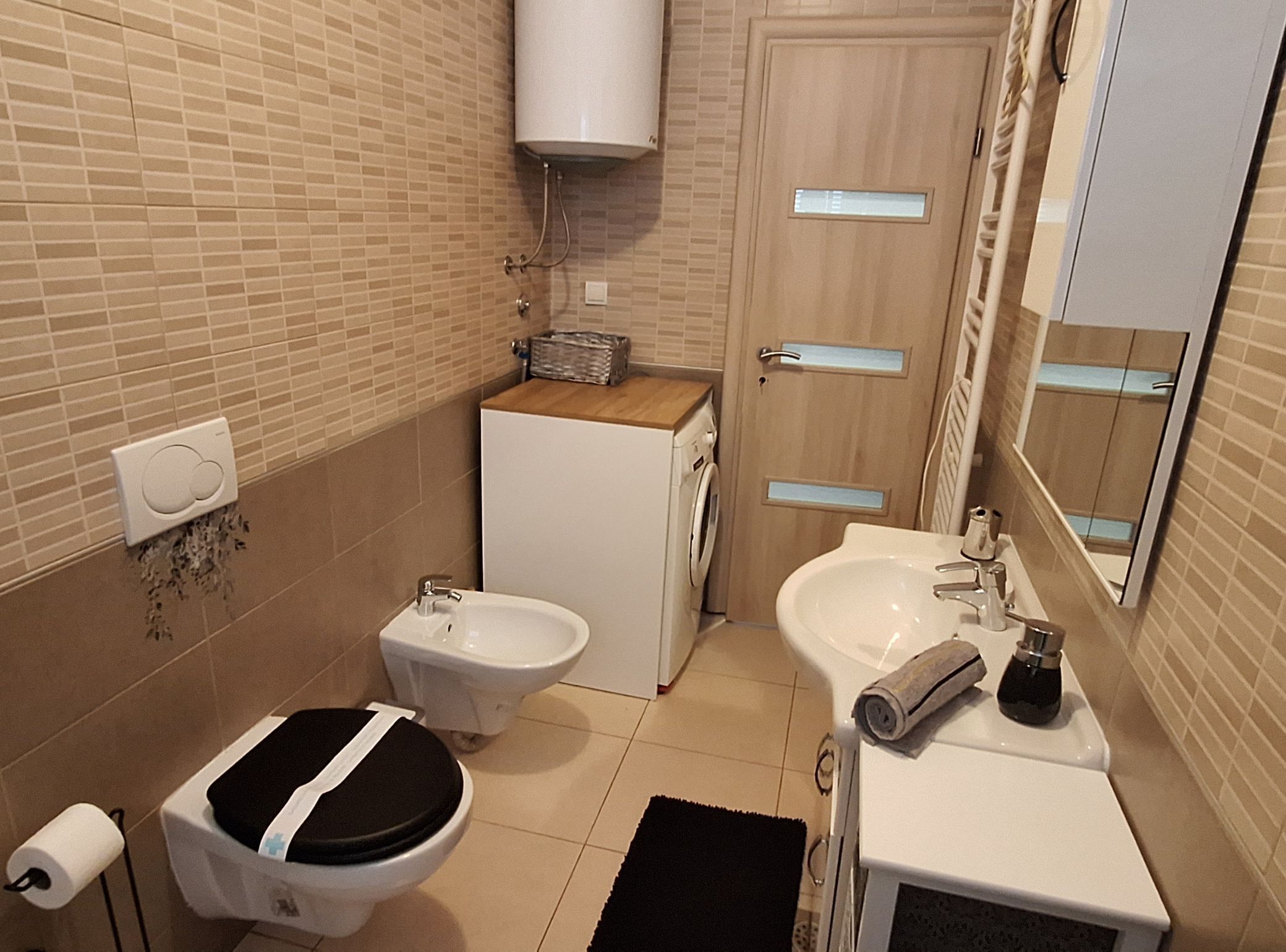 A compact bathroom with a toilet, bidet, sink, and a mirror.