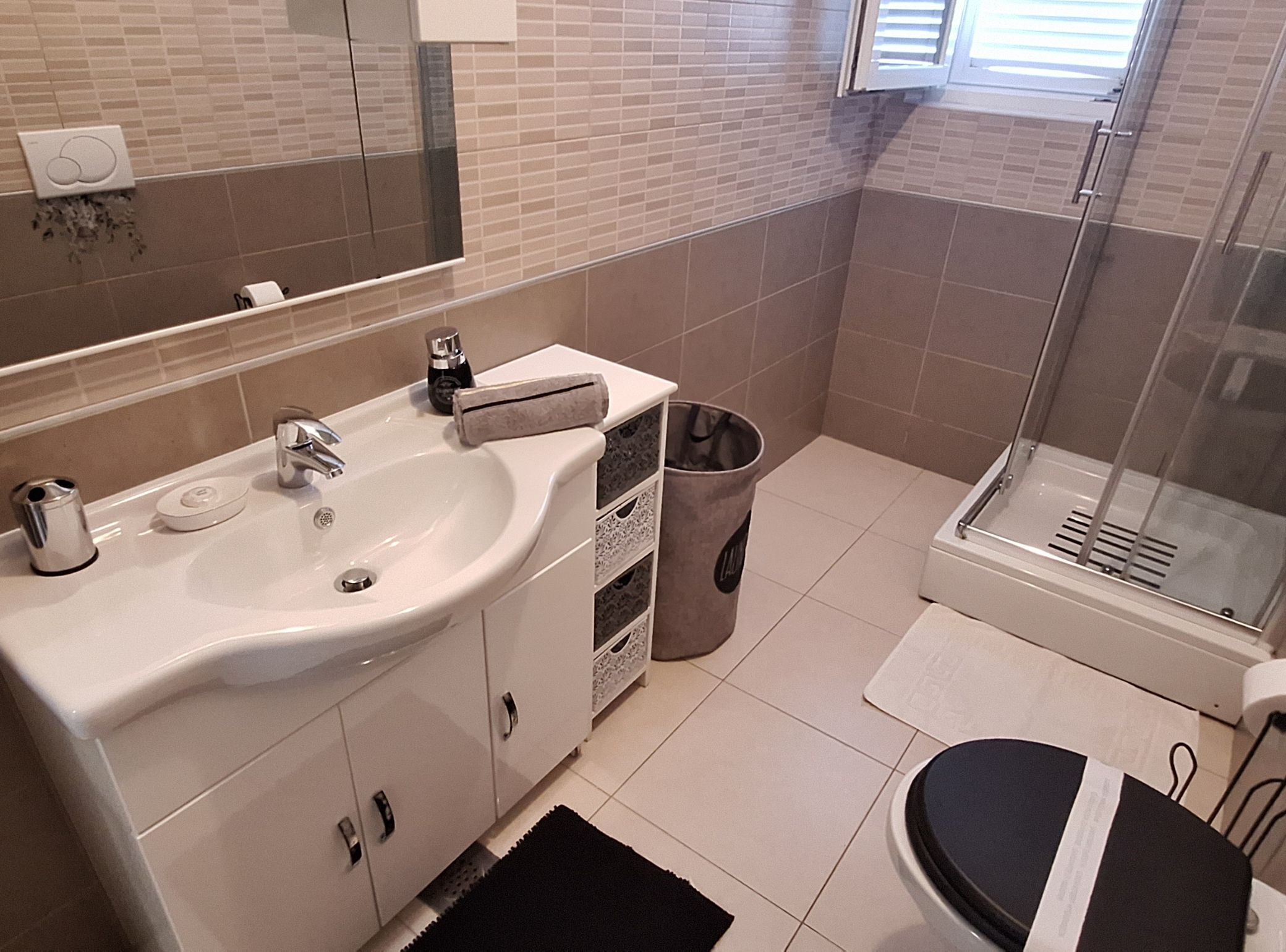 A bathroom with a sink, mirror, and shower.
