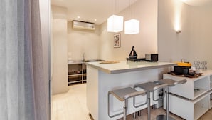 Una cocina moderna con una isla central, taburetes de bar, iluminación colgante y horno empotrado.