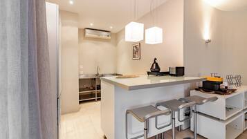 A modern kitchen with a central island, bar stools, pendant lighting, and a built-in oven.