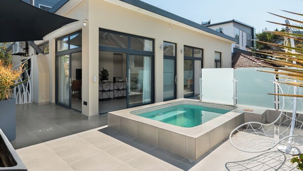 A modern house with a swimming pool, large glass doors, and a patio area. - Three Bedroom Family Haven Sea Point (Cape Town)