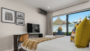 A modern hotel room with a bed, a desk, a television, and framed pictures on the wall. - Three Bedroom Family Haven Sea Point (Cape Town)