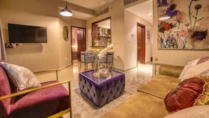 Una sala moderna con un pouf púrpura, un sofá y un comedor.