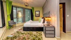 Un dormitorio moderno con cama, una silla, mesita de noche y alfombra estampada.
