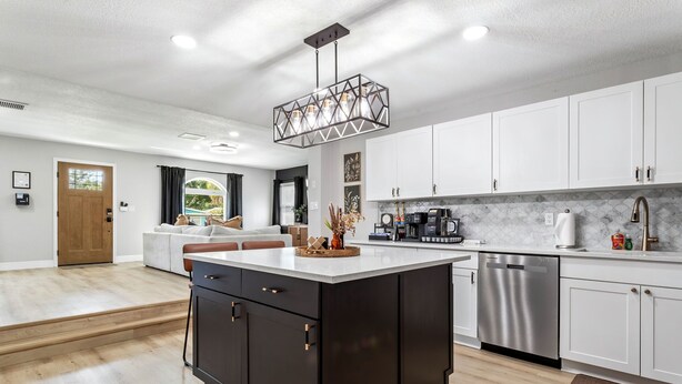 Una cocina moderna con armarios blancos, una isla central y electrodomésticos de acero inoxidable.