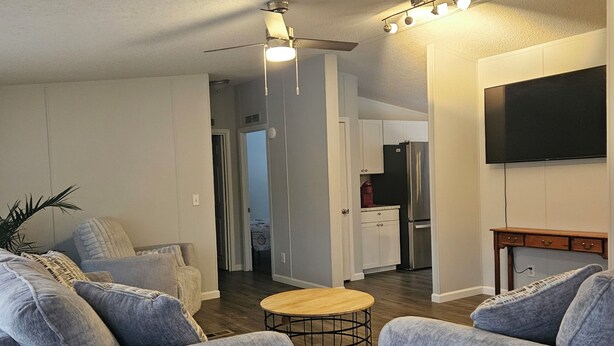A modern living room with grey sofas, a wooden coffee table, and a ceiling fan.