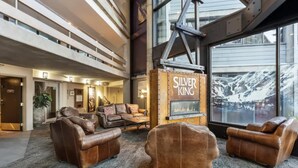 A lobby with leather sofas, a fireplace, and a large window with a mountain view. - SilverKing Mountainside Penthouse - Sleeps 12 (Park City)