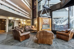 A lobby with leather sofas, a fireplace, and a large window with a mountain view.