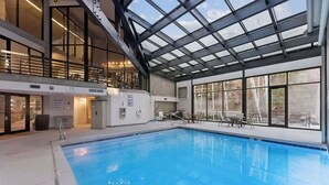 A swimming pool with a glass ceiling, indoor seating, and a view of the outdoors. - SilverKing Mountainside Penthouse - Sleeps 12 (Park City)