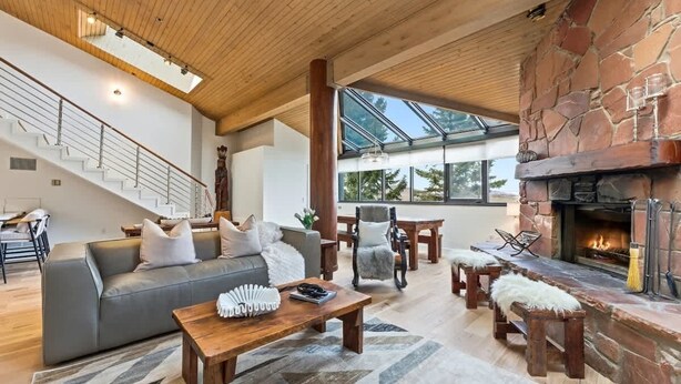 A spacious living area with a stone fireplace, a wooden ceiling, and a staircase. - SilverKing Mountainside Penthouse - Sleeps 12 (Park City)