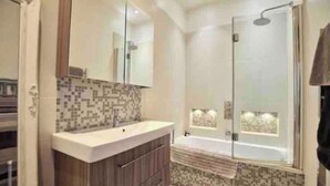 Une salle de bain moderne avec un grand miroir, un meuble-lavabo en bois, une baignoire et une cabine de douche en verre.