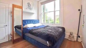 Une chambre à coucher avec un lit, une fenêtre, une porte et une petite statue.