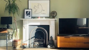 Un salon avec une cheminée, un téléviseur et une grande plante.