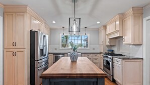 A spacious kitchen with light wood cabinets, stainless steel appliances, and a central island.