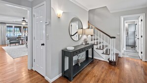 A modern entryway with a dark console table, a round mirror, and a staircase with wooden steps.