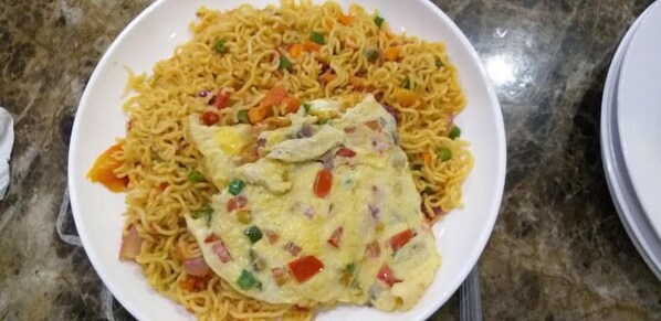 A plate of instant noodles with vegetables and scrambled eggs.