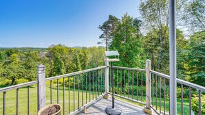 A wooden deck with a metal railing, a bird feeder, and a potted plant. - Mtn-View Retreat in Huson Valley: Great for Groups (Claverack)