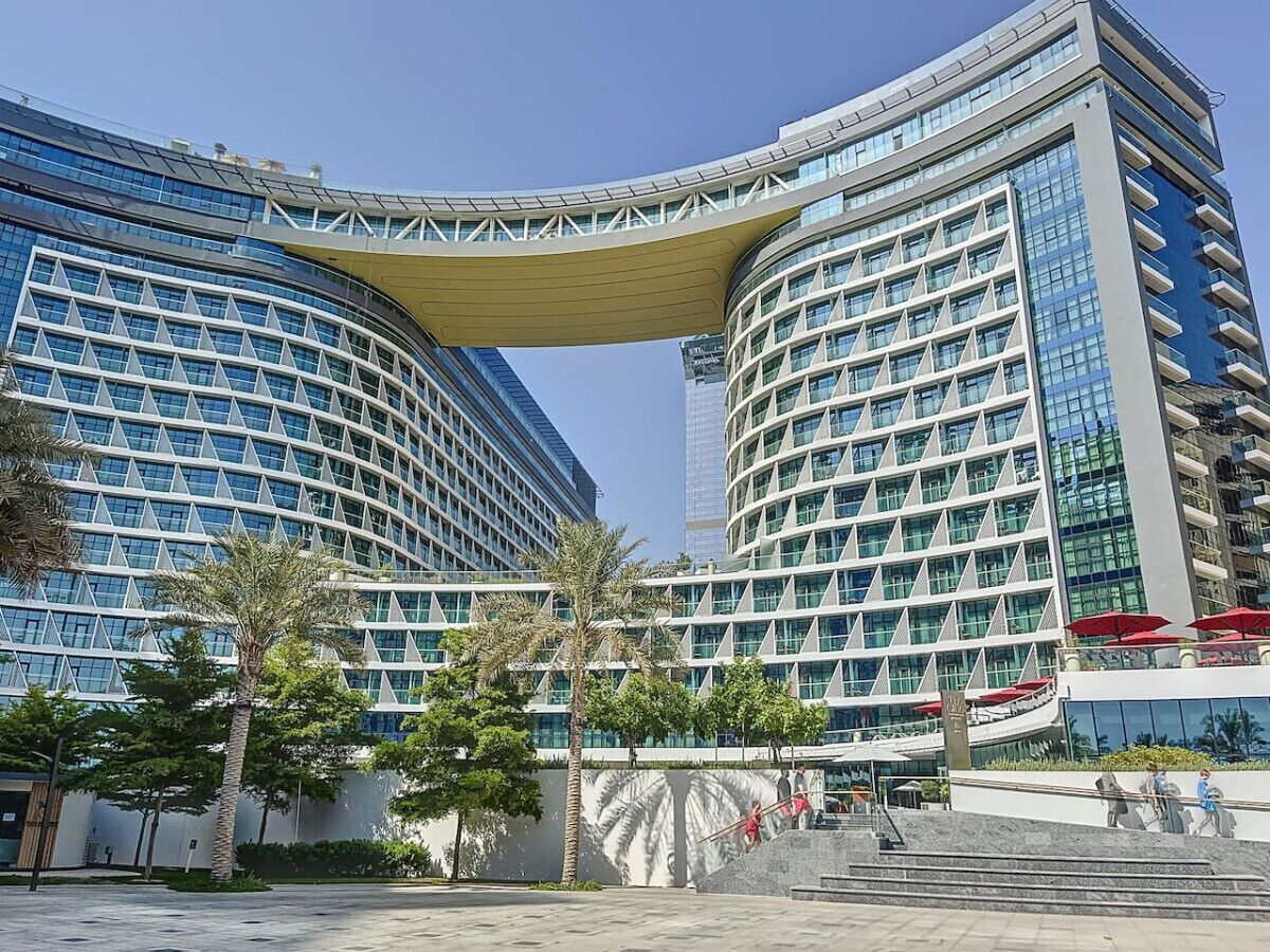 A modern hotel with a curved facade, large windows, and a prominent overhang.