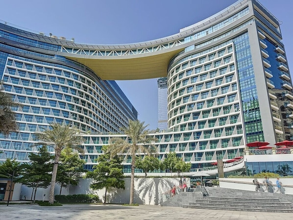 A modern hotel with a curved facade, large windows, and a prominent overhang.