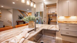Una cocina moderna con encimera de mármol, pileta de acero inoxidable e iluminación colgante.