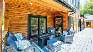 Una terraza de madera con mobiliario exterior, que incluye un sofá y sillas, además de una pequeña mesa.