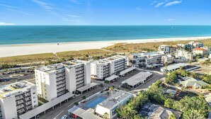 Un hotel frente al mar con varias edificaciones, una piscina y vistas a la playa.