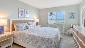 A bedroom with a bed, bedside tables, a nightstand, a dresser, and a window with blinds. - Direct Gulf Views Spacious Siesta Key 2 Bed 2 Bath Condo with Views (Siesta Key)