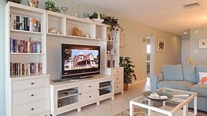 A living room with a TV, bookshelves, a sofa, and a coffee table.