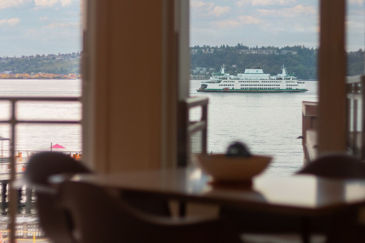 A view from inside a room with a large window overlooking a body of water and a ferry.
