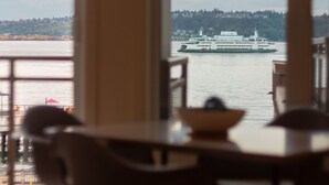 Blick vom Innenraum eines Zimmers mit einem großen Fenster auf ein Gewässer und eine Fähre.