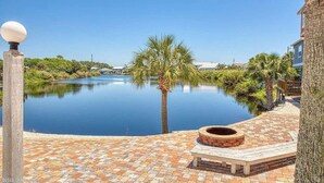 A serene outdoor pool area with a clear view of a calm water body, surrounded by lush greenery and a paved walkway. - Modern One Bedroom Lockout (Panama City Beach)