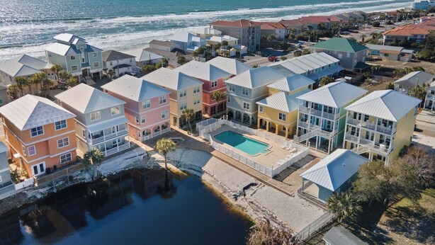 A coastal residential area with colorful houses, a swimming pool, and a view of the ocean. - Modern One Bedroom Lockout (Panama City Beach)