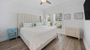A bedroom with a large bed, a ceiling fan, a window with blinds, and a nightstand. - Modern One Bedroom Lockout (Panama City Beach)
