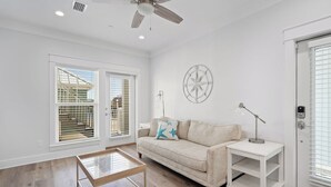 A spacious living room with a wooden floor, a beige sofa, a coffee table, and a ceiling fan. - Modern One Bedroom Lockout (Panama City Beach)