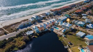 An aerial view of a coastal residential area with houses along the beachfront, a road, and a body of water. - Modern One Bedroom Lockout (Panama City Beach)