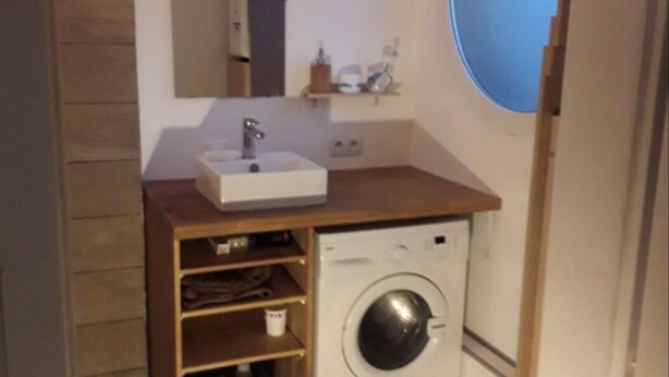 Une petite salle de bain comprenant un lavabo, un miroir et un lave-linge.